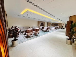 A hotel lobby with a reception desk, seating area with chairs and sofas, and potted plants. - Qira Hotel (Makkah)