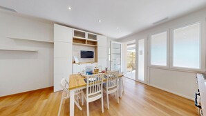 A modern kitchen with white cabinetry, a wooden dining table, and chairs. - Garda Hub Retreat by Booking Garda Lake (Puegnago sul Garda)