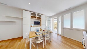 A modern kitchen with white cabinetry, a wooden dining table, and chairs.