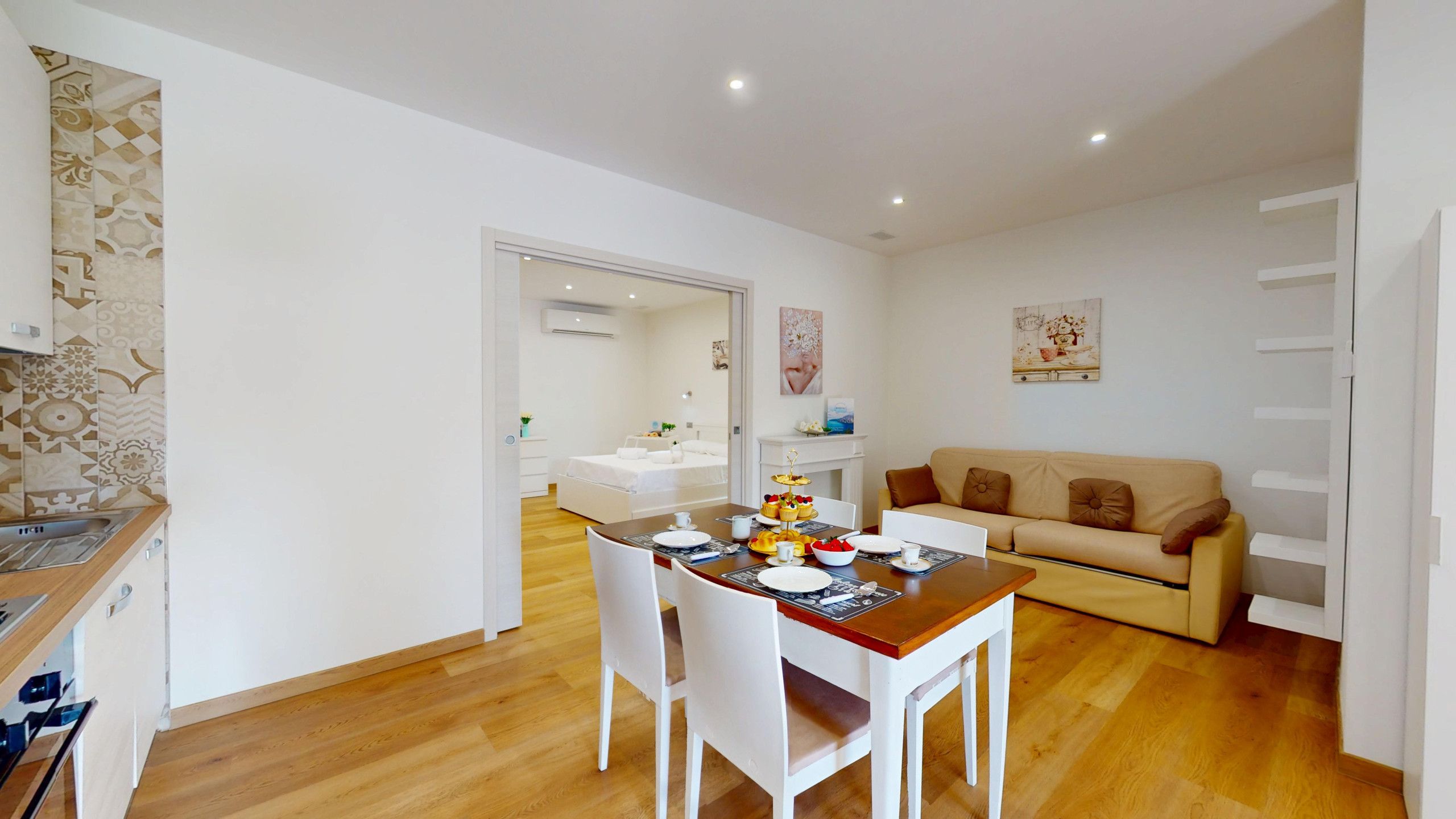 A modern apartment with a dining area, a sofa, and a kitchen.