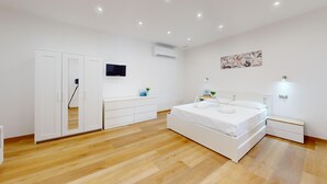 Quarto com cama, guarda-roupa, televisão, ar-condicionado e um quadro na parede.