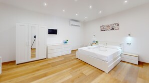 Ein Schlafzimmer mit einem Bett, einem Kleiderschrank, einem Fernseher, einer Klimaanlage und einem Bild an der Wand.
