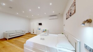 Una habitació d'hotel amb un llit, un sofà, un escriptori i una televisió.