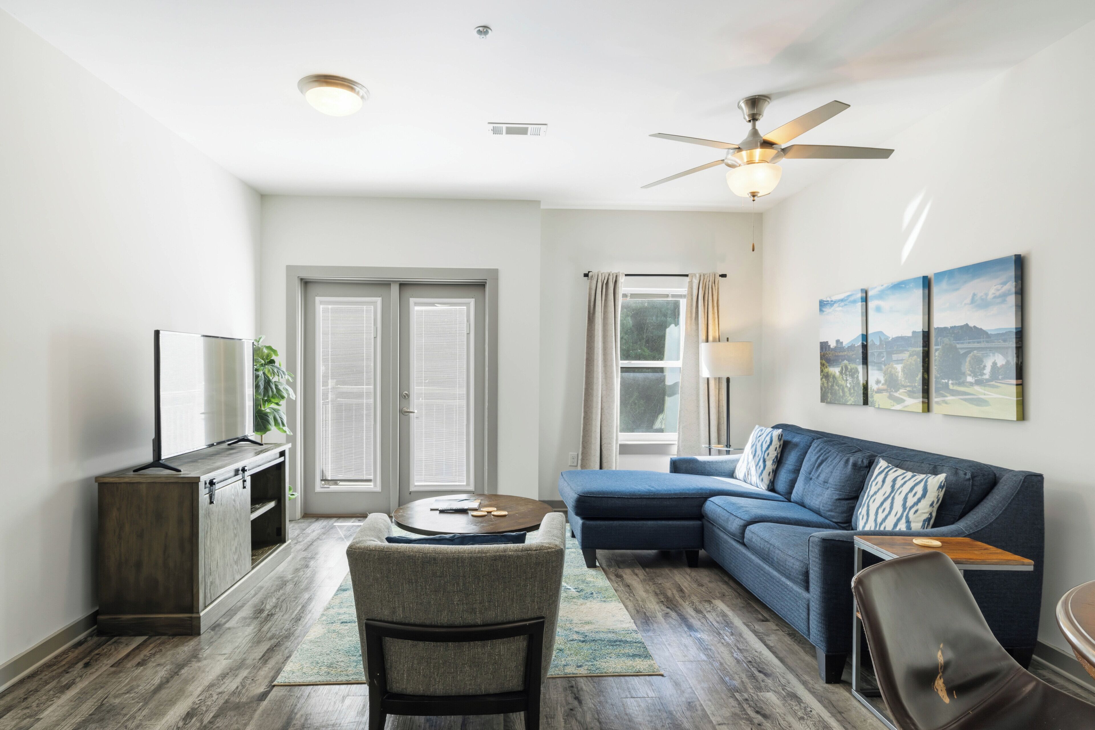 A living room with a sofa, a coffee table, a TV, and a ceiling fan.
