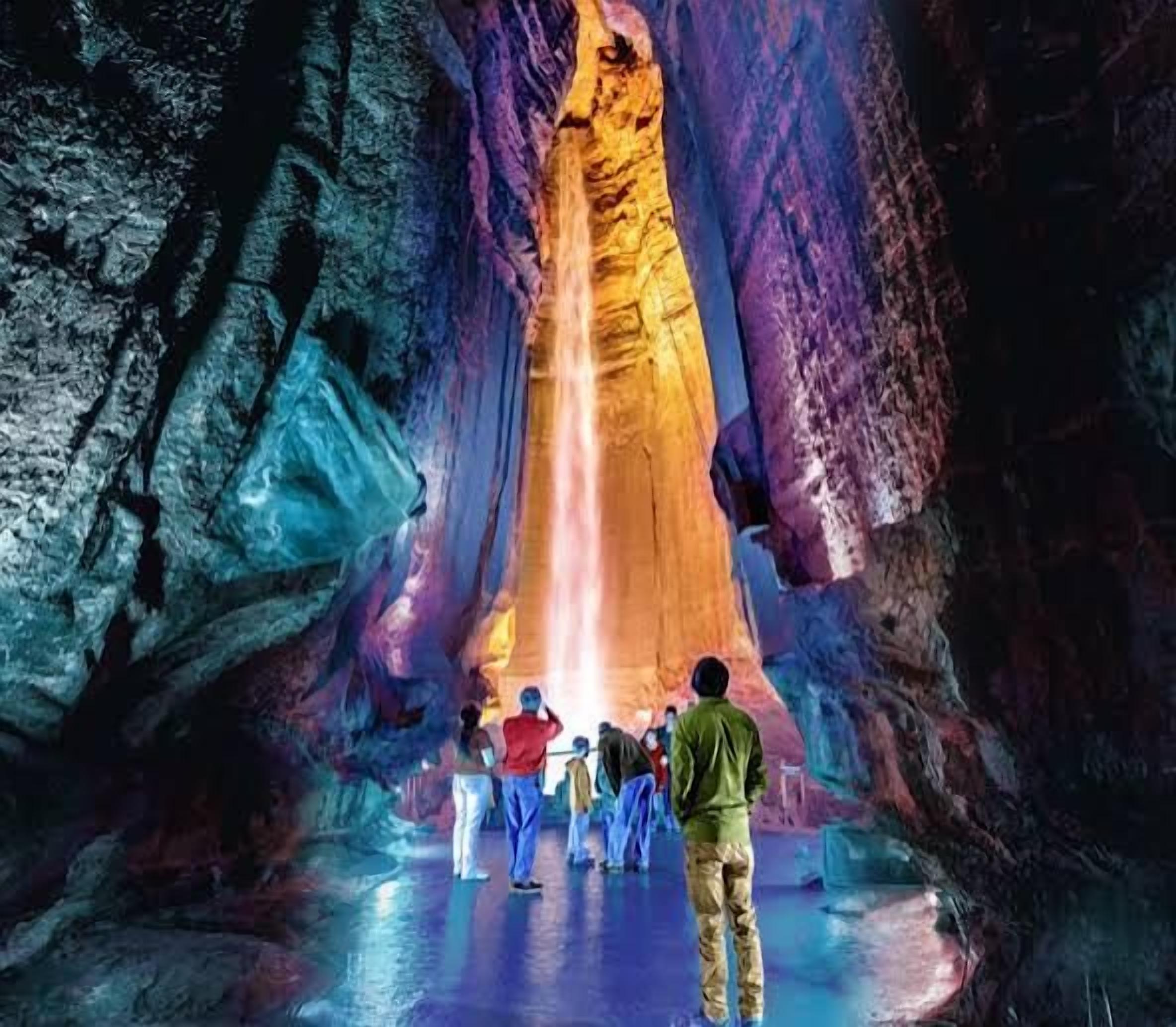 A group of people standing in a cave with a large rock formation.