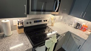 Cocina moderna con microondas, estufa y horno integrados, encimeras de granito y armarios oscuros.