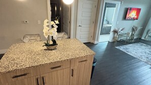 Una cocina moderna con encimera de granito, armarios de madera e iluminación colgante.