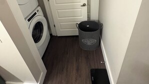 Un lavadero con lavadora, secadora y cesto de ropa.