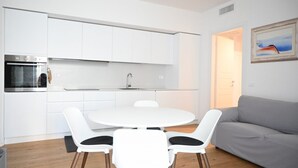 A modern kitchen with white cabinets, a built-in oven, and a round dining table with four chairs. - SE295 - Senigallia, spacious three-room apartment with parking space and garden. (Senigallia)