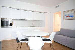 A modern kitchen with white cabinets, a built-in oven, and a round dining table with four chairs. - SE295 - Senigallia, spacious three-room apartment with parking space and garden. (Senigallia)
