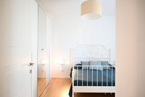A bedroom with a white metal bed frame, a bedside table with a lamp, and a door leading to another room. - SE295 - Senigallia, spacious three-room apartment with parking space and garden. (Senigallia)