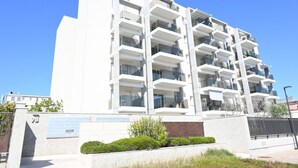 A modern multi-story building with balconies, a clear sky, and a landscaped area in front. - SE295 - Senigallia, spacious three-room apartment with parking space and garden. (Senigallia)