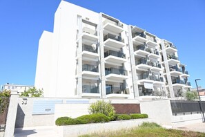 A modern multi-story building with balconies, a clear sky, and a landscaped area in front. - SE295 - Senigallia, spacious three-room apartment with parking space and garden. (Senigallia)