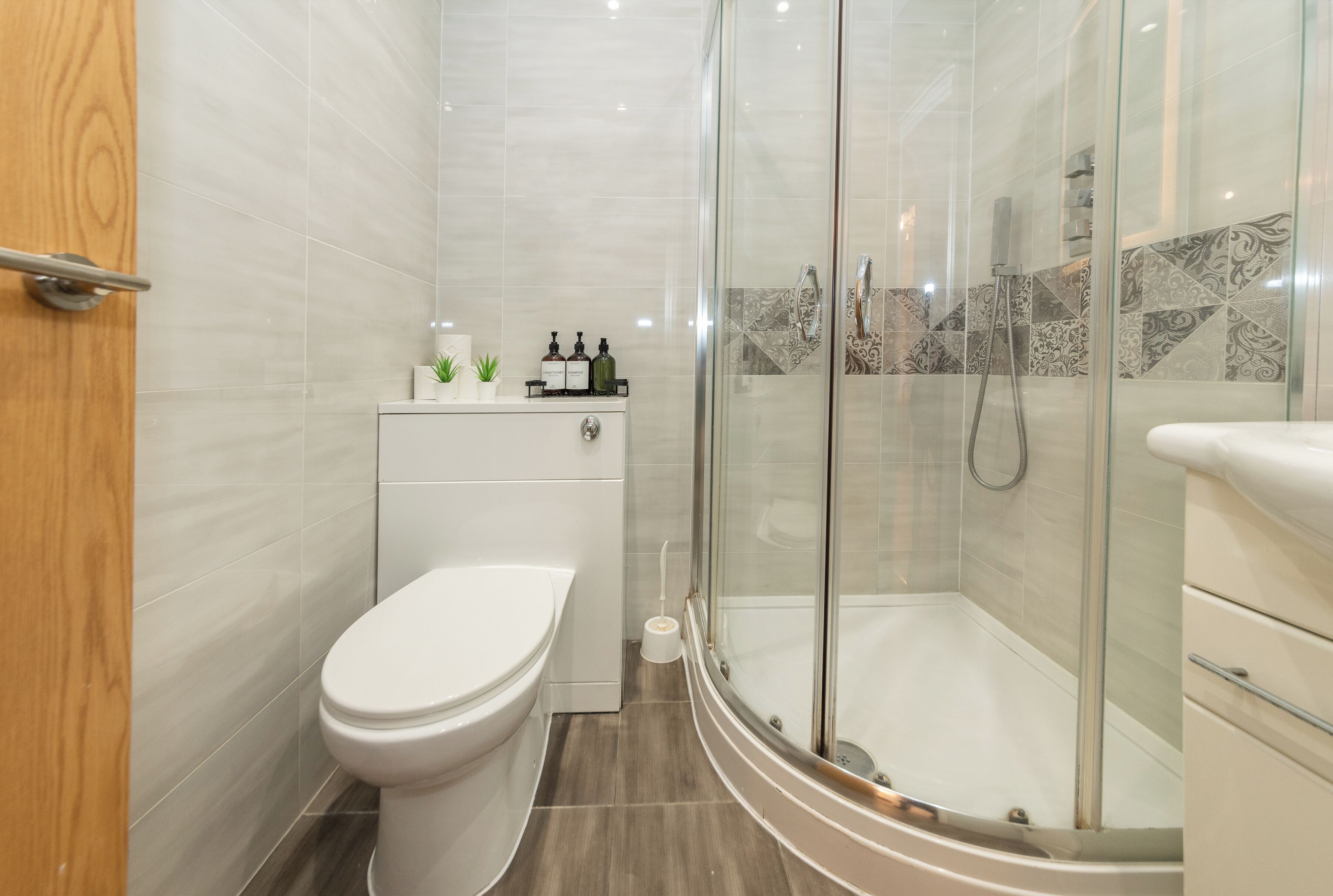 A modern bathroom with a toilet, a glass-enclosed shower, and a vanity with a mirror.
