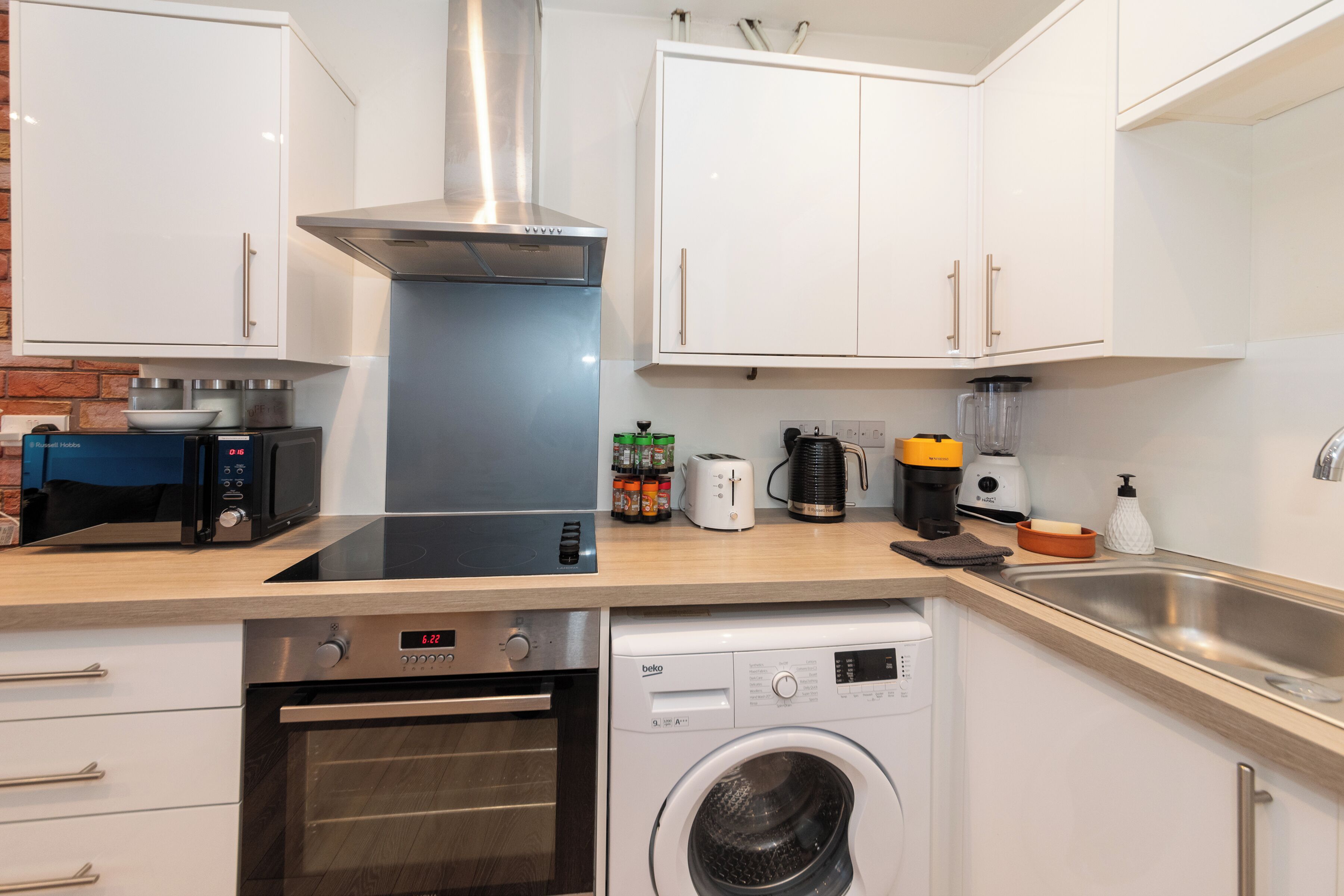 A modern kitchen with a built-in oven, microwave, and dishwasher, along with a coffee maker and toaster.