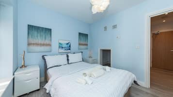 A bedroom with a bed, nightstands, and artwork on the walls.