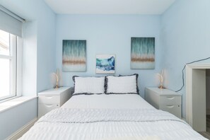 Un dormitorio con una cama, dos mesitas de noche y tres cuadros colgados en la pared.