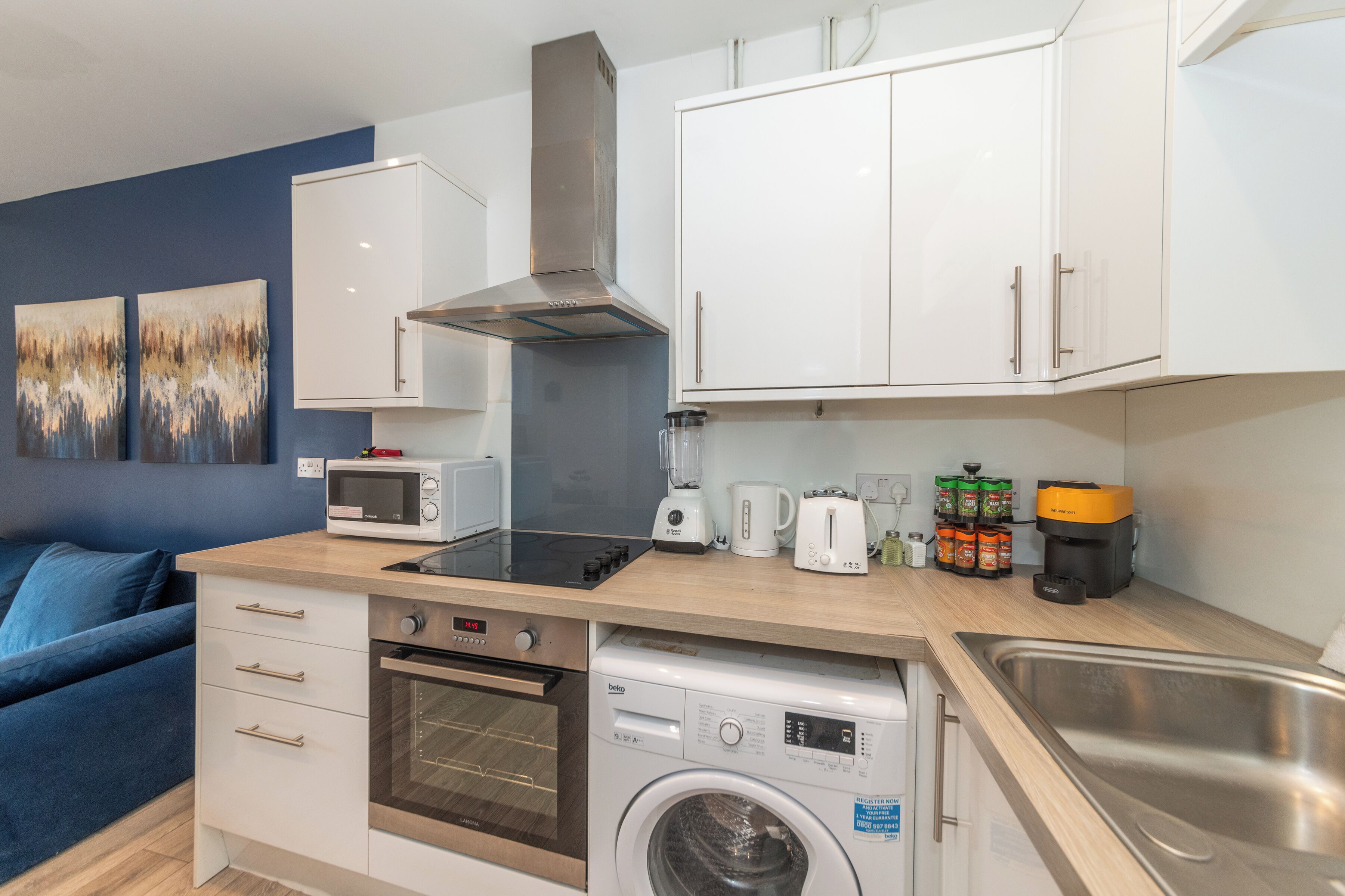 A compact kitchenette with a microwave, toaster, coffee maker, and a coffee machine.