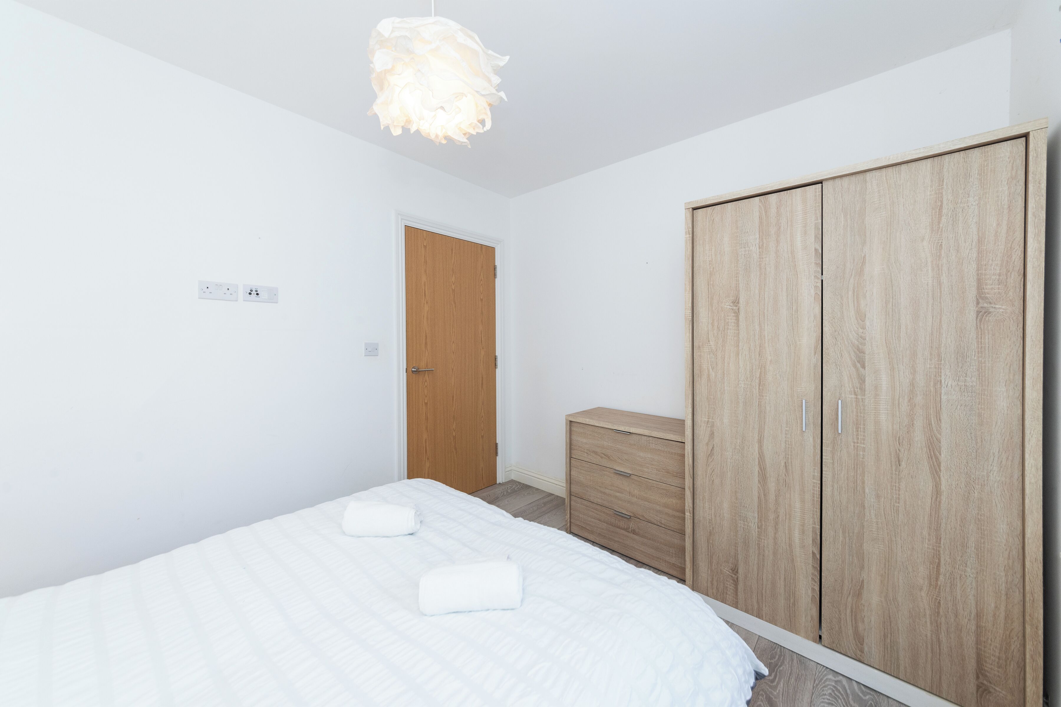 Ein Schlafzimmer mit einem Bett, einem Kleiderschrank und einer Pendelleuchte.