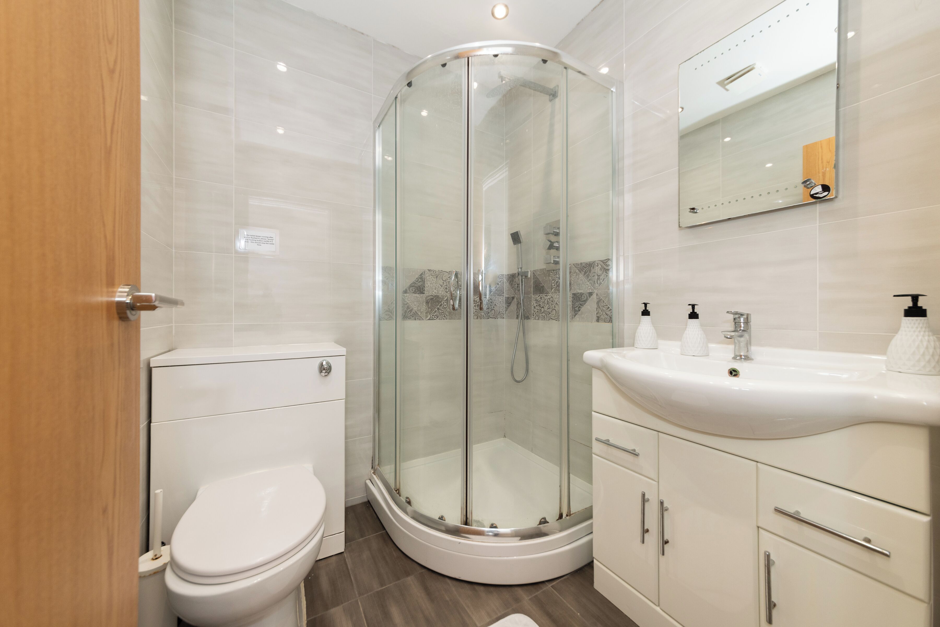 A modern bathroom with a glass-enclosed shower, a toilet, and a vanity with a sink and storage.