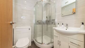 A modern bathroom with a glass-enclosed shower, a toilet, and a vanity with a sink and storage.
