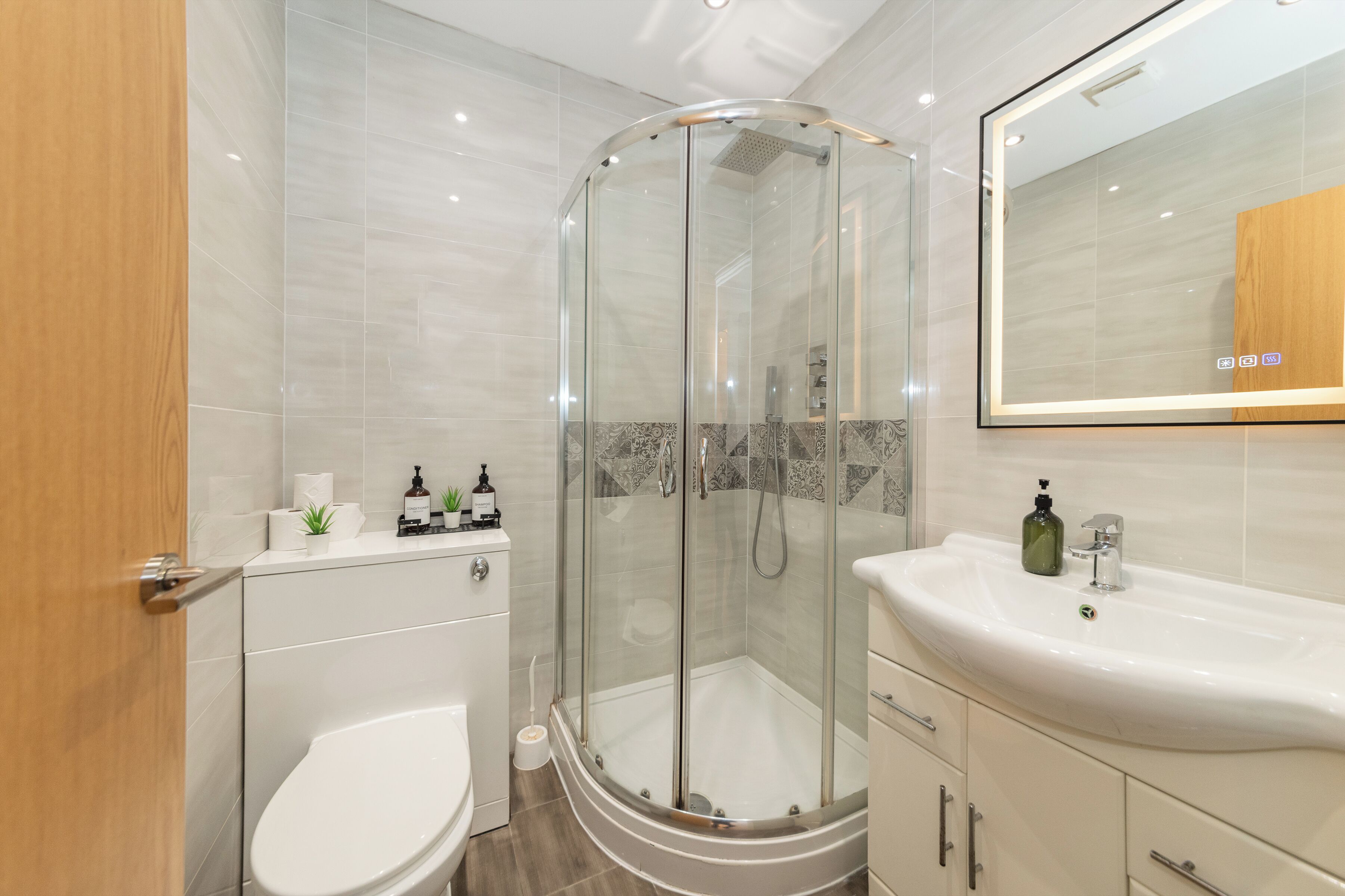 A modern bathroom with a glass-enclosed shower, a white sink, and a toilet.