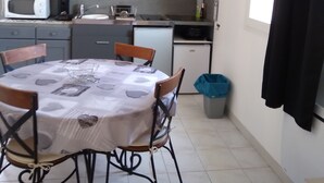 Et lille køkken med spisebord, stole, mikrobølgeovn, vask og et minikøleskab.