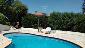 En swimmingpool med buet kant, omgivet af stentrellis.