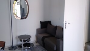 En stue med sofa, rundt spejl, gulvlampe og lille bord.