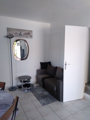 Ein Wohnzimmer mit einer Couch, einem runden Spiegel, einer Stehlampe und einem kleinen Tisch.