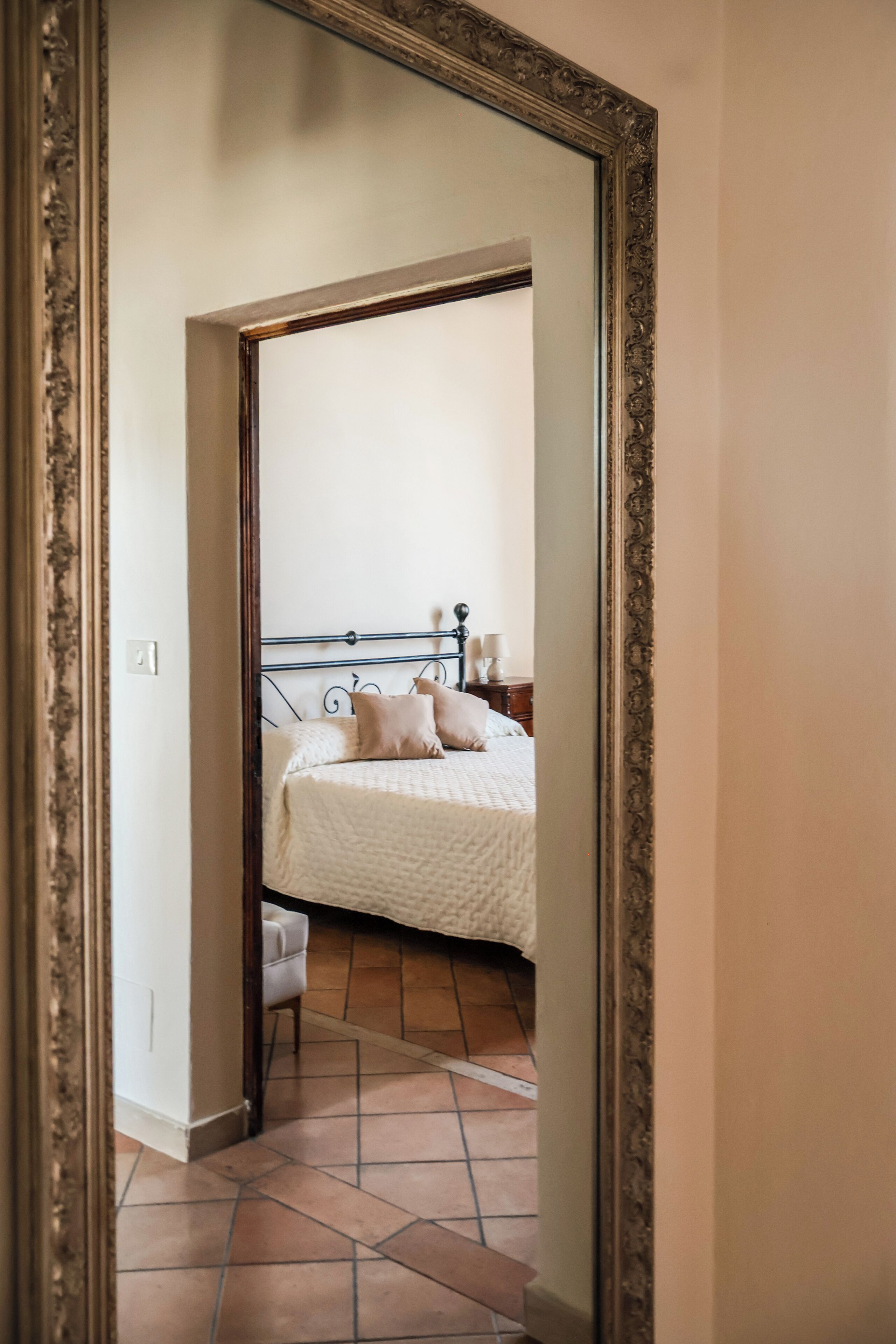 Un dormitorio con cama, mesita de noche, lámpara y una silla.