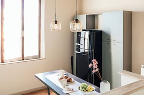 A modern kitchen with a black refrigerator, a dining table with breakfast items, and pendant lights. - La Casa sul Corso - Nel cuore di Foiano della Chiana (Foiano della Chiana)