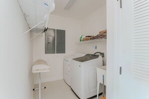 Un'area lavanderia con lavatrice, stendibiancheria e uno scaffale con asciugamani piegati.