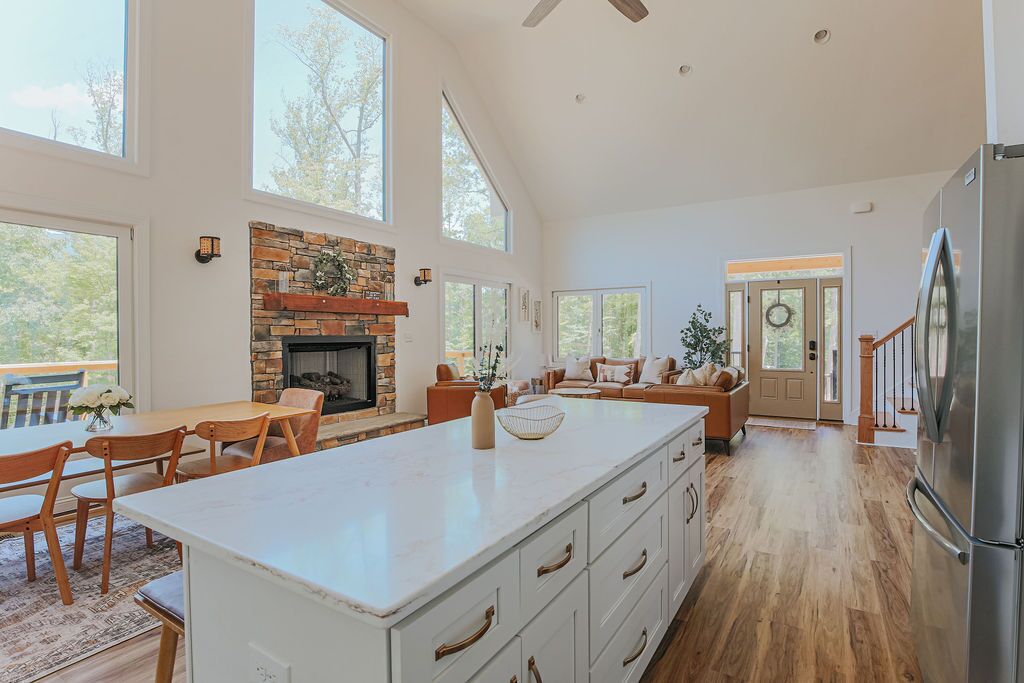 A spacious kitchen with a large island, a stone fireplace, and a view of the outdoors.