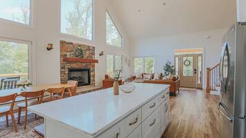 A spacious kitchen with a large island, a stone fireplace, and a view of the outdoors.