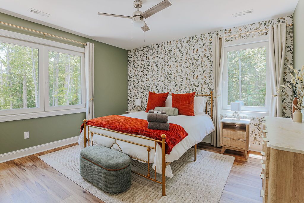 A bedroom with a bed, a nightstand, a chair, and a window.