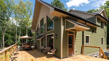 A two-story house with a deck, outdoor furniture, and a covered patio area.