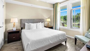 Hotelkamer met een bed, twee nachtkastjes, een bankje en een raam met uitzicht op groen.