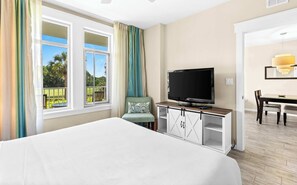 Une chambre d’hôtel avec un lit, un téléviseur posé sur une commode en bois, une chaise et une table à manger.