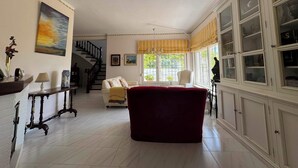 Uma sala de estar ampla com escada, um sofá vermelho e um armário com portas de vidro.