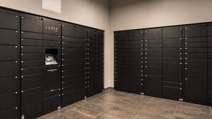 A row of black lockers with numbers on them, a sign that says 'LUXER ONE', and a website address 'LuxeroOne.com' on one of the lockers. - Downtown Miami Boutique Residence with Rooftop Pool, Gym, Cowork & Den (Miami)