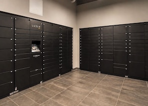 A row of black lockers with numbers on them, a sign that says 'LUXER ONE', and a website address 'LuxeroOne.com' on one of the lockers. - Downtown Miami Boutique Residence with Rooftop Pool, Gym, Cowork & Den (Miami)