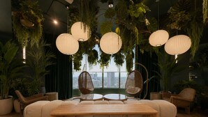 A modern lounge with a sofa, round tables, hanging planters, and a view of the city. - Downtown Miami Boutique Residence with Rooftop Pool, Gym, Cowork & Den (Miami)