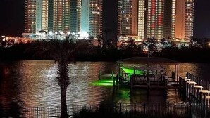 A nighttime view of a high-rise building with multiple floors, a dock, and a small body of water. - Relaxing, water front rental in Orange Beach with pool access and boat slip. (Orange Beach)