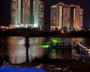 A nighttime view of a high-rise building with multiple floors, a dock, and a small body of water. - Relaxing, water front rental in Orange Beach with pool access and boat slip. (Orange Beach)