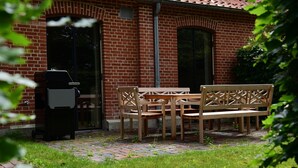 A brick building with a patio area featuring a wooden table and chairs, a grill, and a grassy lawn. - Exclusive "Backbord" vacation rental with private boat access and dock (Boren)