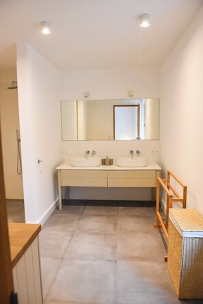 Ein Badezimmer mit zwei Waschbecken, einem Spiegel und einer Dusche.