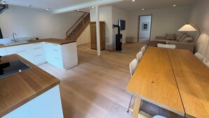 A modern kitchen with white cabinets and a wooden countertop, a dining area with a wooden table and chairs, and a living room with a sofa and a television. - Exclusive "Backbord" vacation rental with private boat access and dock (Boren)