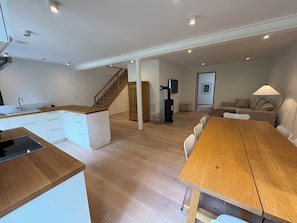 A modern kitchen with white cabinets and a wooden countertop, a dining area with a wooden table and chairs, and a living room with a sofa and a television. - Exclusive "Backbord" vacation rental with private boat access and dock (Boren)