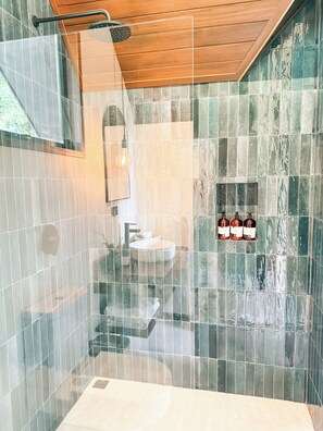 Ein modernes Badezimmer mit Duschkabine aus Glas, Holzboden und Fliesenwand.